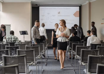 Professionals at a business conference engage before a presentation in a modern office.