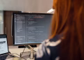 A female engineer works on code in a contemporary office setting, showcasing software development.