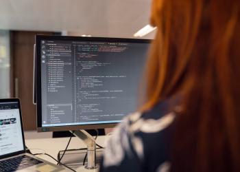 A female engineer works on code in a contemporary office setting, showcasing software development.