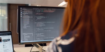 A female engineer works on code in a contemporary office setting, showcasing software development.