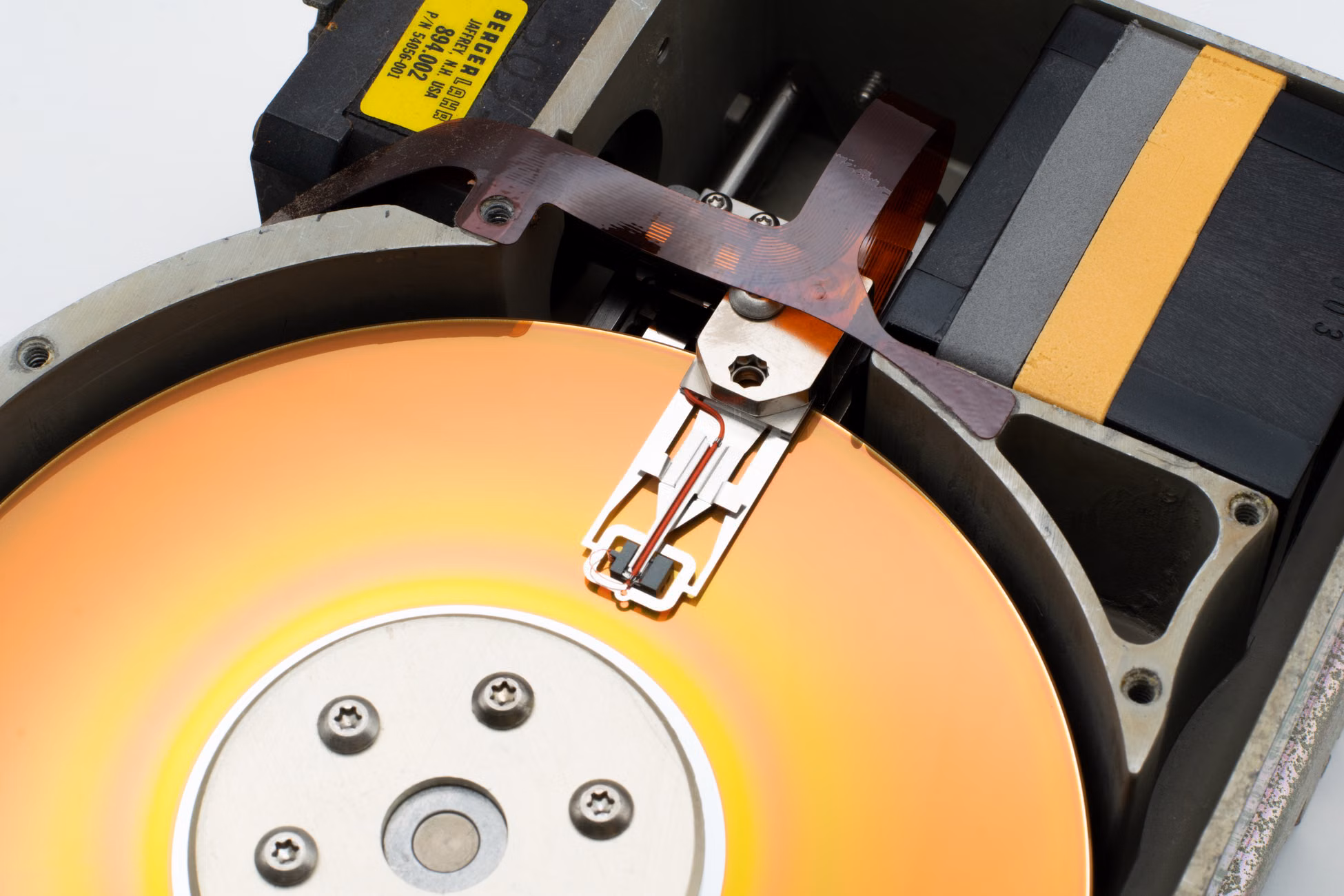 Detailed view of a vintage hard disk drive showing the read/write head and spinning platter.