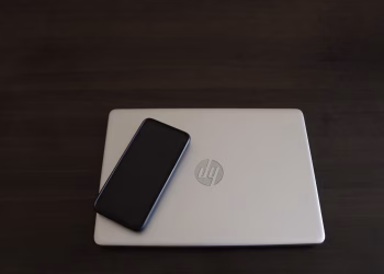 Close-up of a smartphone resting on an HP laptop, symbolizing modern technology integration.