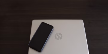 Close-up of a smartphone resting on an HP laptop, symbolizing modern technology integration.