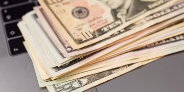 Stack of US dollar bills on a keyboard, symbolizing digital finance and wealth.