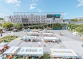A vibrant outdoor market celebrating Asia Culture Week with stalls and greenery.