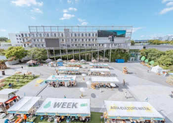 A vibrant outdoor market celebrating Asia Culture Week with stalls and greenery.