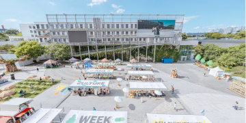 A vibrant outdoor market celebrating Asia Culture Week with stalls and greenery.