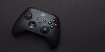 Closeup of a black gaming controller on a dark backdrop, perfect for tech themes.
