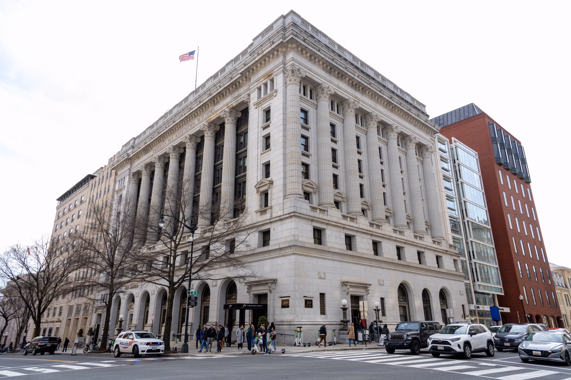 Street view of an iconic historic building in Washington D.C. with cars and pedestrians on a sunny day.