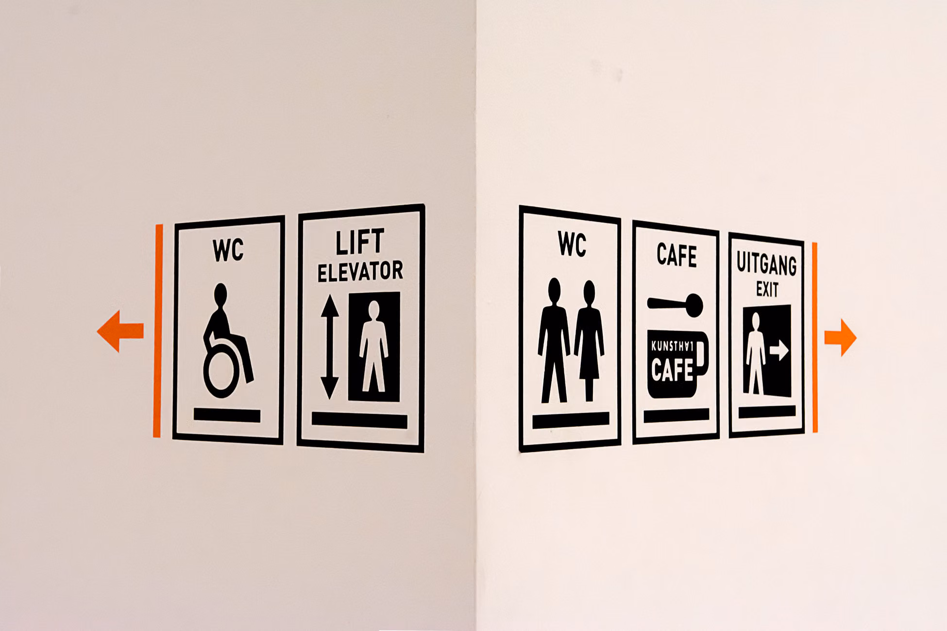 Close-up of wall signs including WC, elevator, cafe, and exit directions.