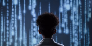 A young boy viewing a digital screen with data streams, symbolizing technology interaction.