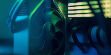 Detailed close-up of a computer cooling fan inside a custom PC with LED lighting, emphasizing technology and design.
