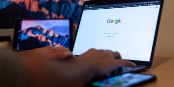 Hands typing on a laptop with Google on screen, in a remote work setup in Milan, Italy.
