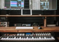 Professional music production setup featuring keyboard, computer screens, and audio equipment.