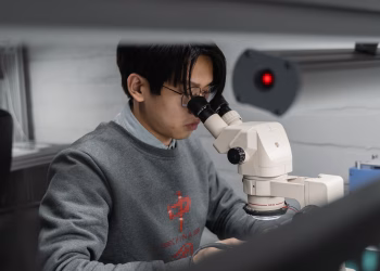 A man using a microscope for scientific research in a laboratory setting.