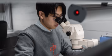 A man using a microscope for scientific research in a laboratory setting.