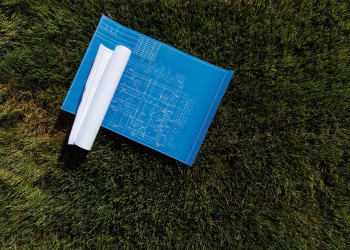 Top view of architectural blueprints on a grassy field, ideal for construction themes.