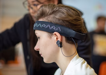 Close-up of a young woman wearing an EEG headband, showcasing modern technology indoors.