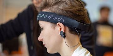 Close-up of a young woman wearing an EEG headband, showcasing modern technology indoors.