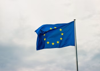 European Union flag waving vividly against a cloudy sky in Strasbourg, France.