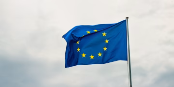 European Union flag waving vividly against a cloudy sky in Strasbourg, France.