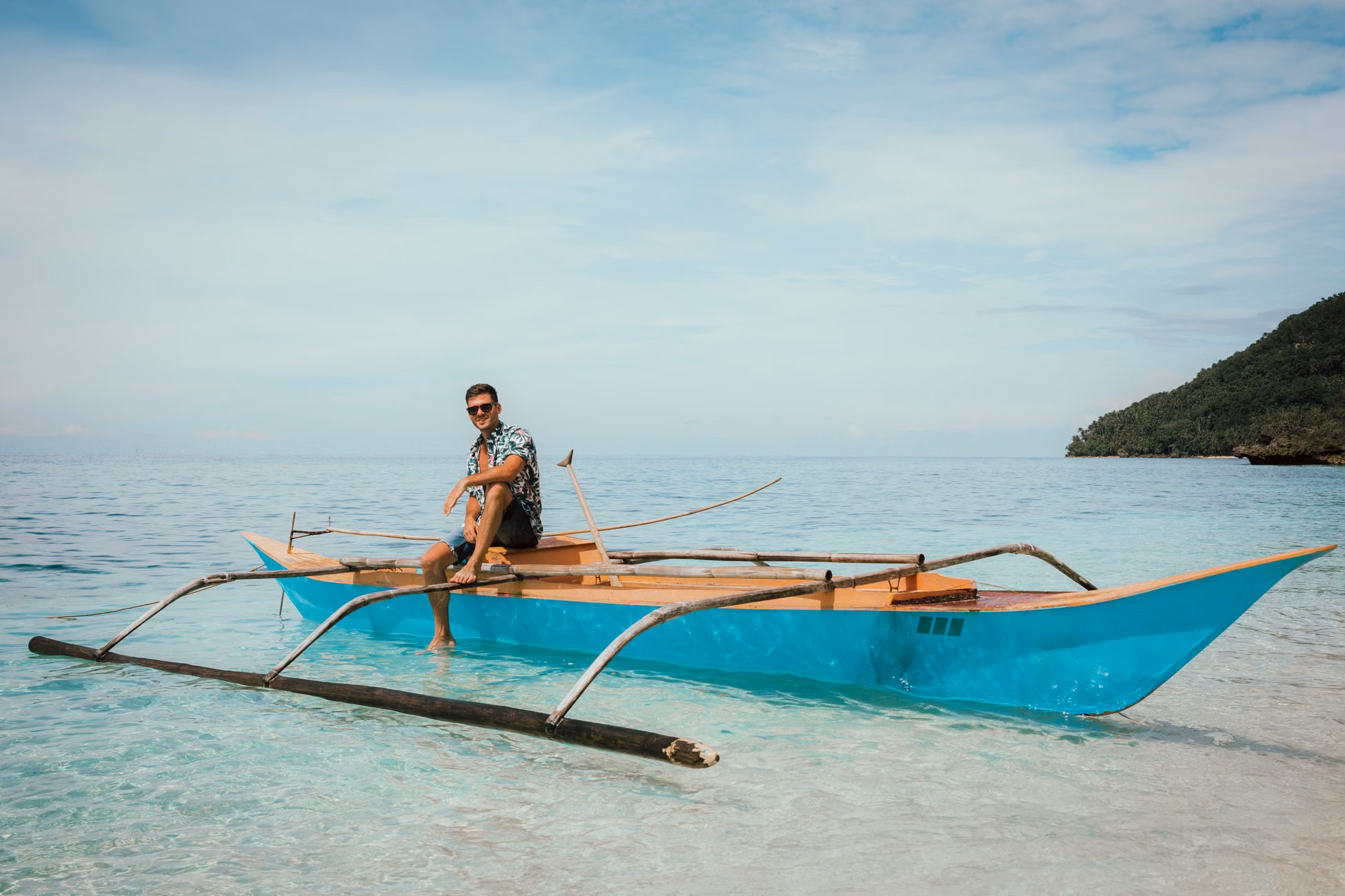 Relaxed man sitting on wooden vessel and relaxing against cloudy blue sky in sea