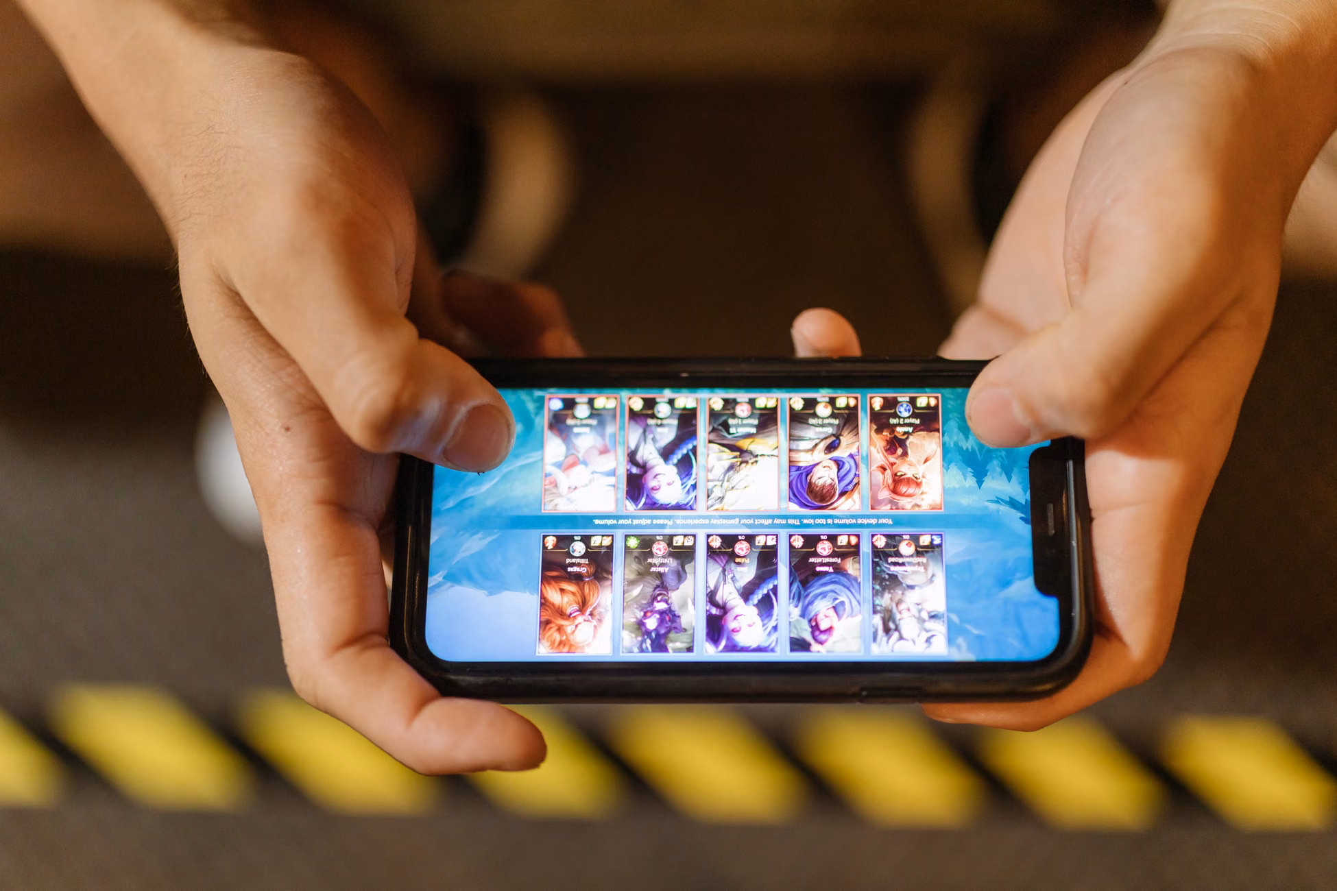 Close-up of hands playing a mobile game on a smartphone, showcasing the game's interface.