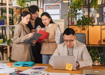 Group of colleagues engaged in a team meeting in a vibrant, plant-filled office.