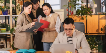 Group of colleagues engaged in a team meeting in a vibrant, plant-filled office.