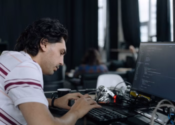 A coder intensely typing at a workstation in a contemporary office setup.