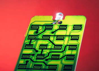 Close-up of a green circuit with intricate patterns on a vibrant red background, ideal for technology themes.