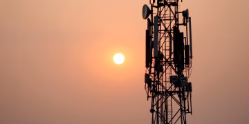 A striking silhouette of a communication tower against a vibrant sunset sky.