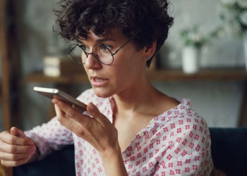 Casual woman using voice command on smartphone at home.