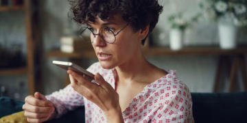 Casual woman using voice command on smartphone at home.