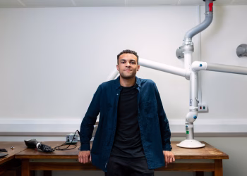 Confident young engineer standing in a laboratory with advanced robotic equipment.