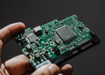 Close-up view of a green circuit board held by a hand, showcasing technology details.