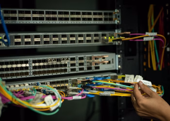 A hand managing fiber optic cables in a server room, showcasing modern connectivity.