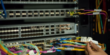 A hand managing fiber optic cables in a server room, showcasing modern connectivity.
