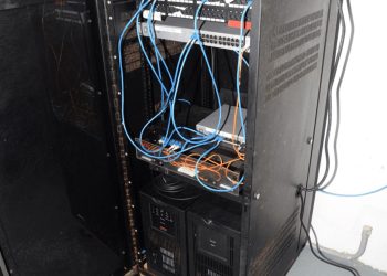 EFTA00002004 - Open server rack with blue and orange cables connected to networking equipment in a utility room