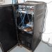 EFTA00002004 - Open server rack with blue and orange cables connected to networking equipment in a utility room