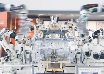 Robotic arms assembling a car chassis on a factory line.