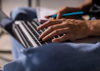 Close-up of a person typing on a laptop, symbolizing technology and remote work.