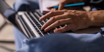 Close-up of a person typing on a laptop, symbolizing technology and remote work.