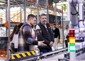 Men observe automated conveyor belt system in warehouse