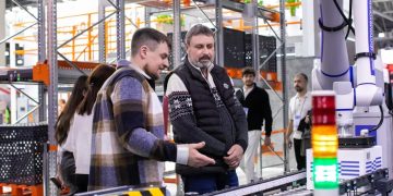 Men observe automated conveyor belt system in warehouse