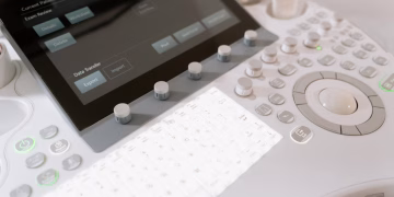 Detailed view of a medical ultrasound machine control panel with buttons and screen.