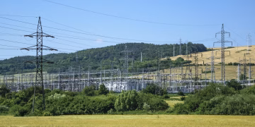 Electric transmission towers against a rural landscape, showcasing energy infrastructure.