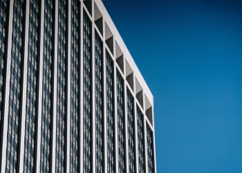Low angle facade of contemporary multistory skyscraper with many windows against blue sky