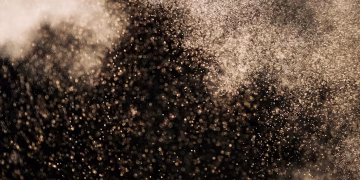 Stunning abstract image featuring gold particles floating against a dark background, creating a magical atmosphere.