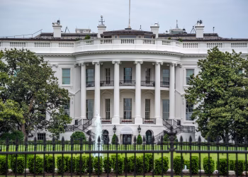 A classic view of the White House in Washington DC with lush greenery and fountains.